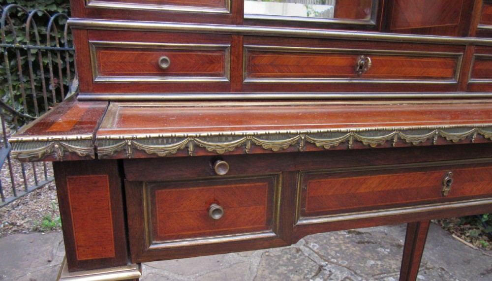 A late 19th-century rosewood bonheur du jour writing desk featuring brass gallery railings, an arched central mirror, multiple small drawers, and tapered legs. View VIII