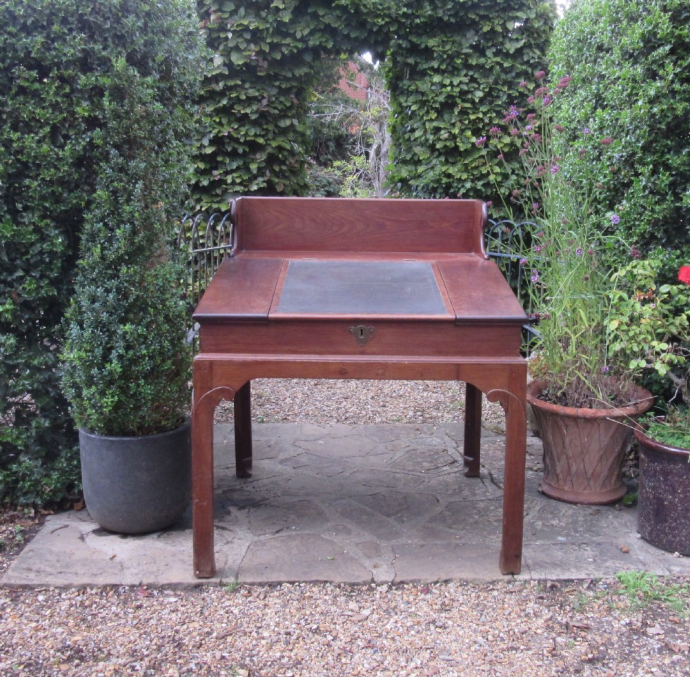 A Georgian mahogany estate desk featuring a slanted writing surface with a dark inset leather skiver, raised scrolled gallery back, and square legs with decorative corner spandrels. View II