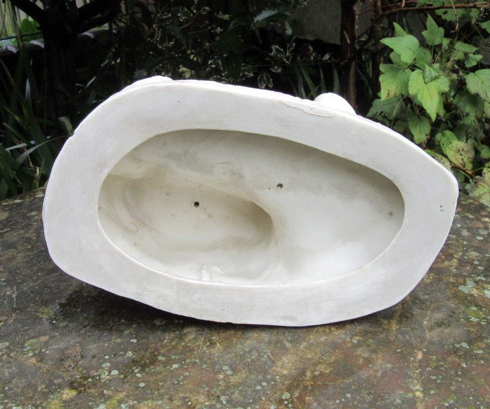 A white unglazed Parian porcelain sculpture depicting two young children sitting beside a sleeping cat on a naturalistic rock base. View V