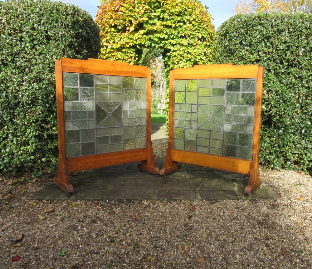 A pair of Art Deco medium oak screens featuring geometric leaded textured glass panels and stepped feet.