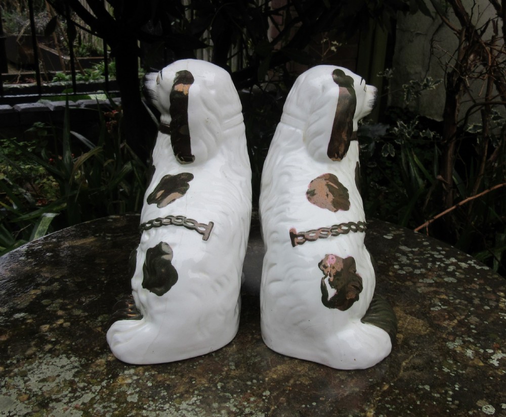 A pair of Victorian ceramic Staffordshire spaniel figurines featuring white glazed bodies with painted faces and copper lustre spots, ears, and moulded chains. View III