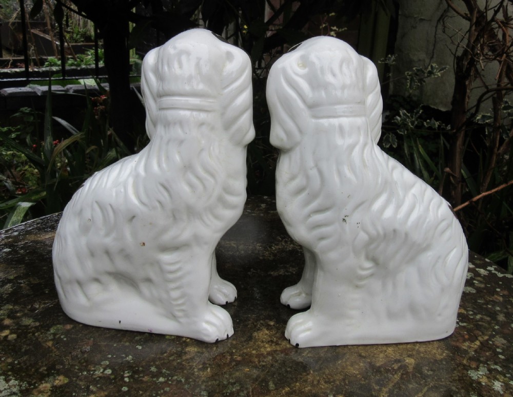 A pair of Victorian ceramic Staffordshire spaniel figurines featuring white glazed bodies with painted faces and copper lustre spots, ears, and moulded chains. View V