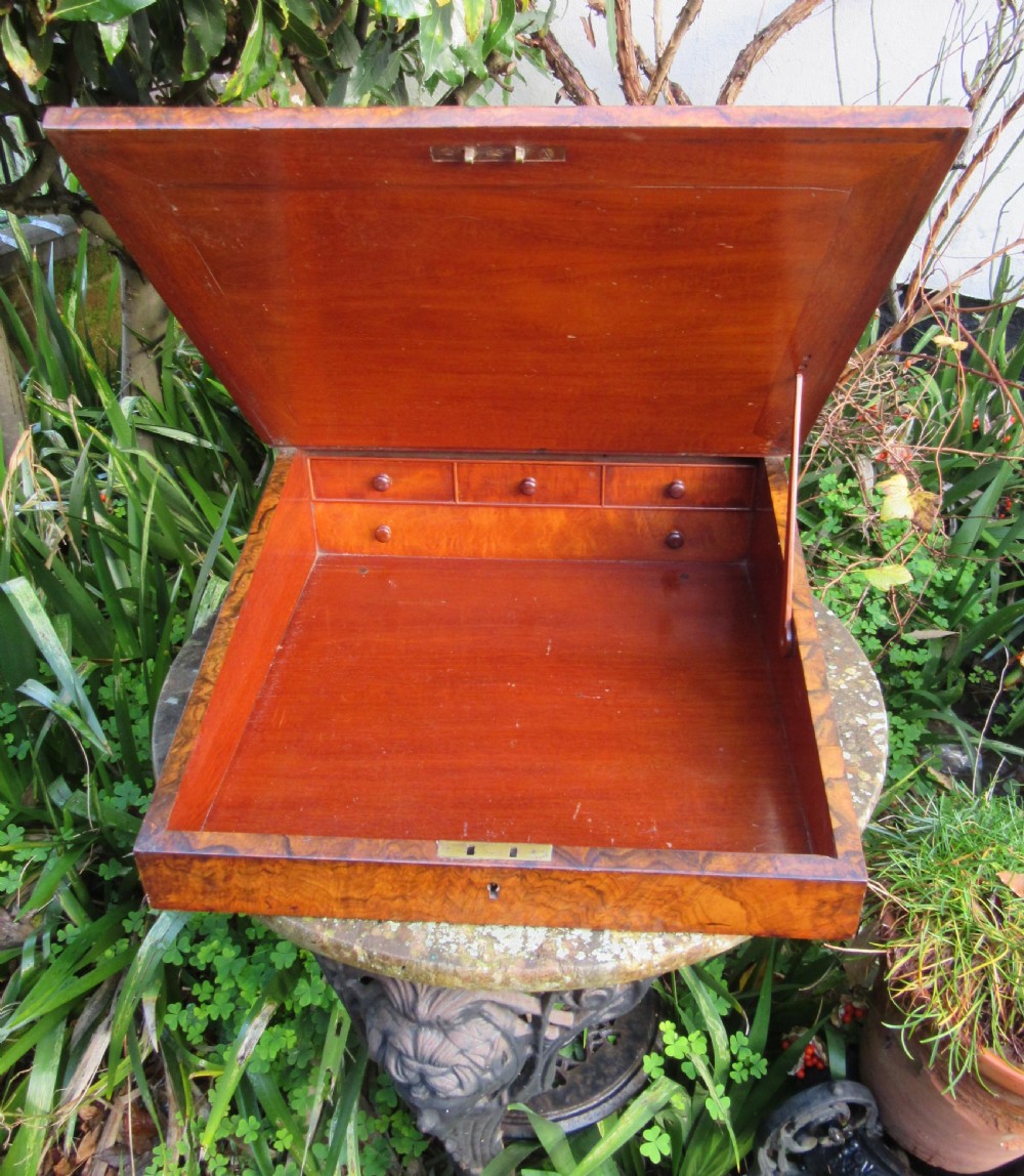 An antique Victorian figured walnut writing slope featuring a brass gallery rail and a brown leather writing surface with decorative gold tooling. View III