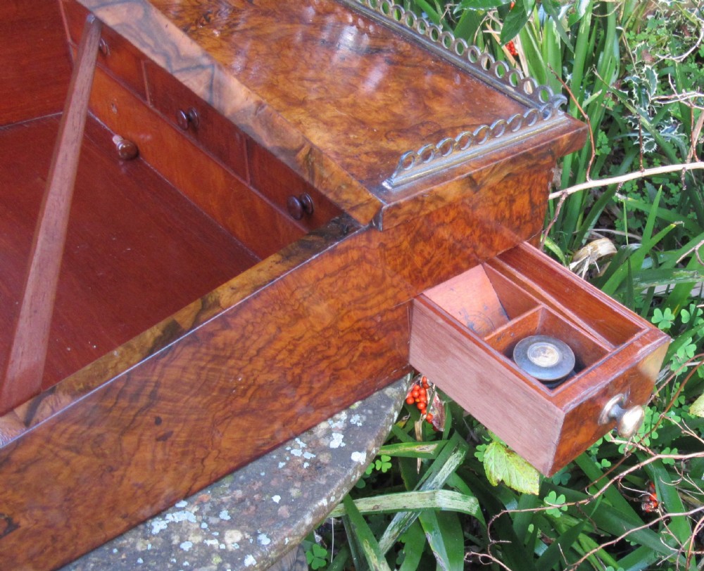 An antique Victorian figured walnut writing slope featuring a brass gallery rail and a brown leather writing surface with decorative gold tooling. View V