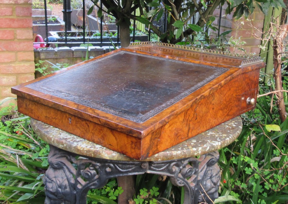 An antique Victorian figured walnut writing slope featuring a brass gallery rail and a brown leather writing surface with decorative gold tooling. View VIII