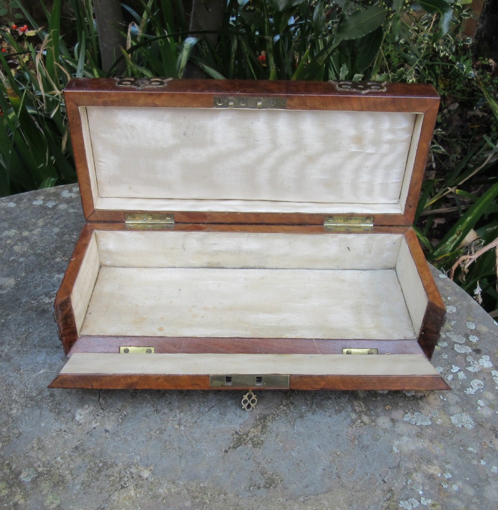 A mid-19th-century domed-top box crafted from warm brown burr walnut wood, featuring ornate pierced brass strapwork mounts, a top handle, and a key inserted into the front lock. View IV