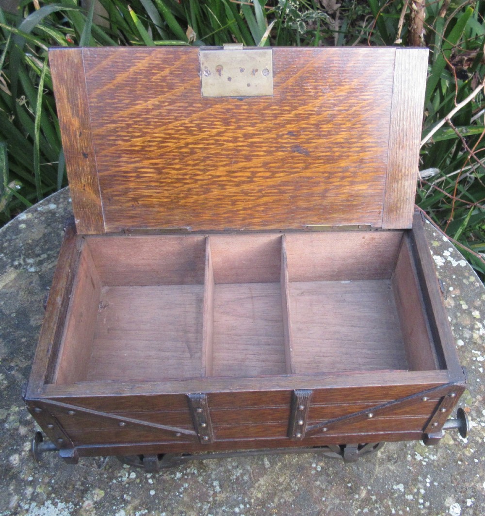 A late Victorian oak humidor designed in the form of a miniature railway coal wagon with metal wheels, buffers, and brass studs. View II