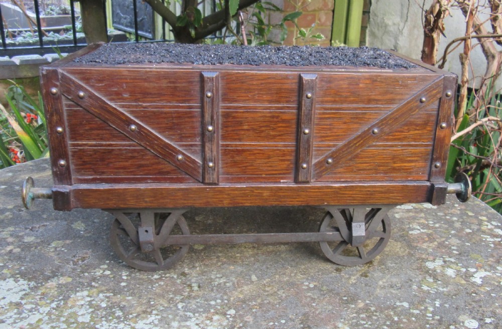 A late Victorian oak humidor designed in the form of a miniature railway coal wagon with metal wheels, buffers, and brass studs. View III