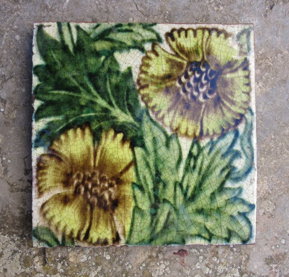 A square Arts and Crafts glazed earthenware tile featuring yellow floral motifs and green foliage with visible crazing on a terracotta base. View II