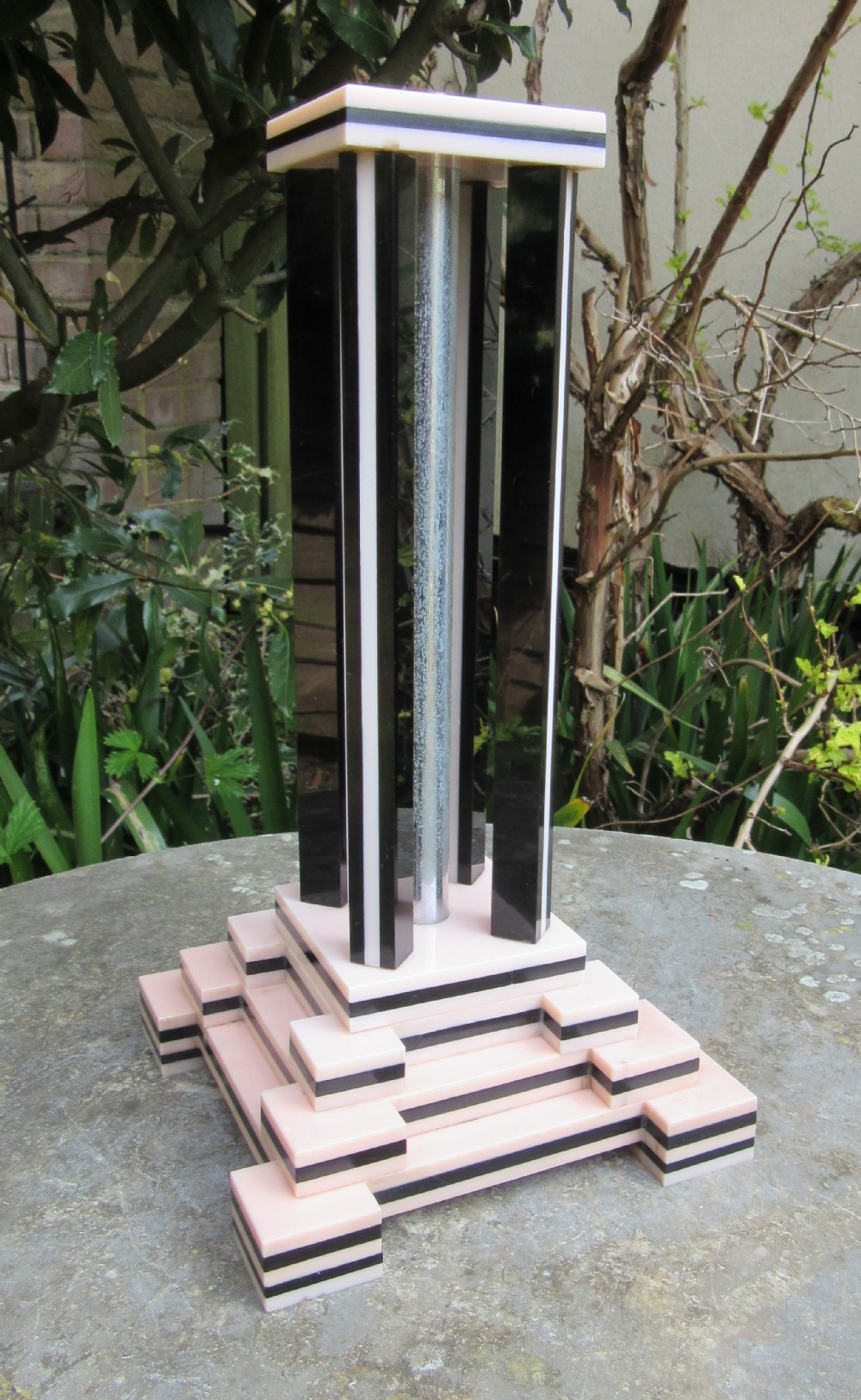 An Art Deco table lamp base featuring a stepped ziggurat foundation and vertical black and pink layered columns.