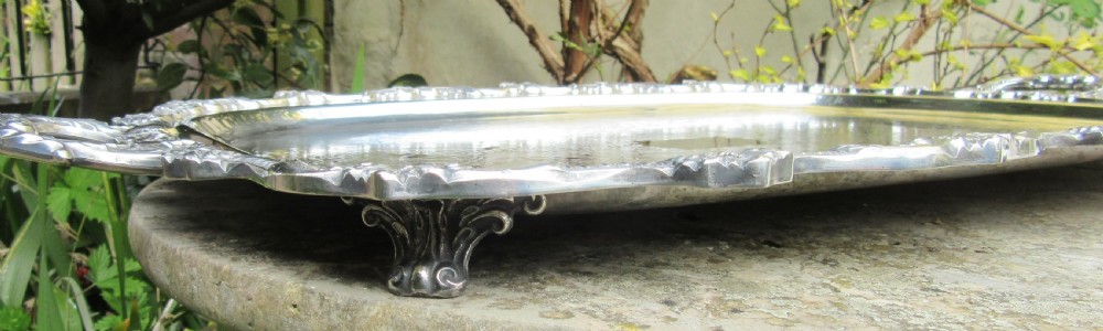 A rectangular Victorian silver-plated tray featuring engraved foliate scrollwork, a shell motif border, and twin cast handles. View IV