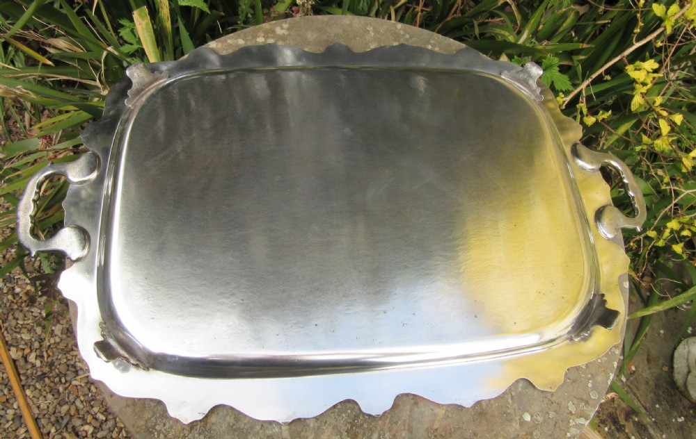 A rectangular Victorian silver-plated tray featuring engraved foliate scrollwork, a shell motif border, and twin cast handles. View V