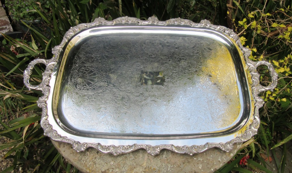 A rectangular Victorian silver-plated tray featuring engraved foliate scrollwork, a shell motif border, and twin cast handles. View VIII