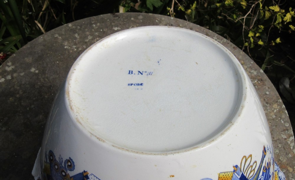 An antique ceramic water jug decorated with blue and yellow floral motifs, classical urns, and a marbled rim border. View V
