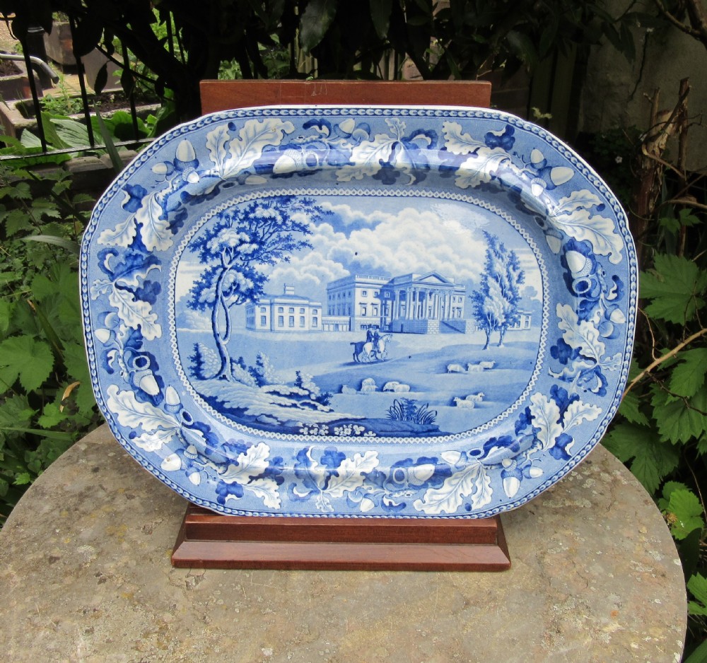 A rectangular blue and white transferware earthenware platter with rounded corners depicting a stately country estate encircled by an oak leaf border.
