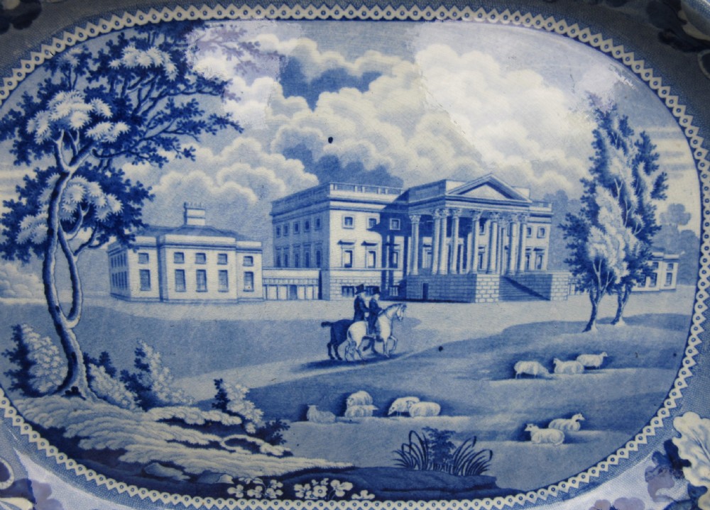 A rectangular blue and white transferware earthenware platter with rounded corners depicting a stately country estate encircled by an oak leaf border. View II