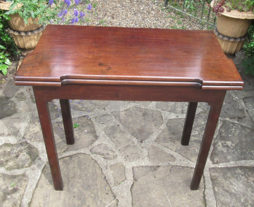 A Georgian mahogany fold-over card table with shaped outset corners and four square straight legs. View II