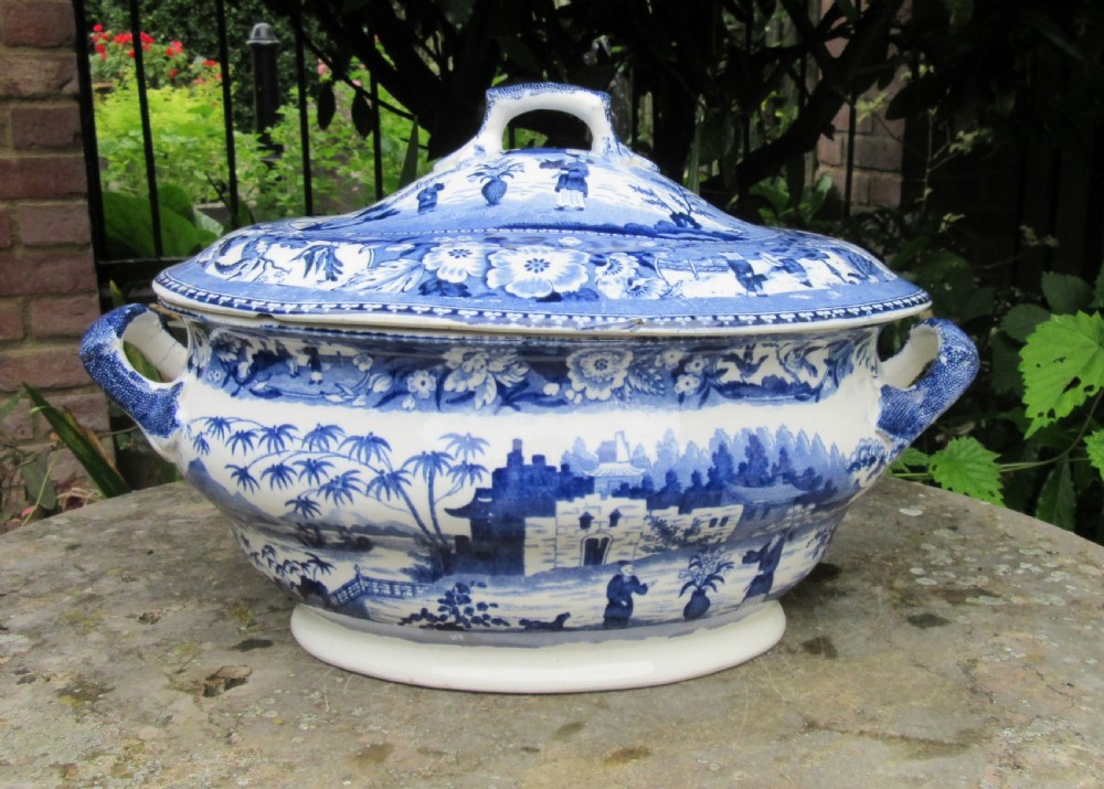 An antique 1830 Staffordshire earthenware tureen featuring blue and white Chinoiserie transferware decoration with a matching lid and side handles.