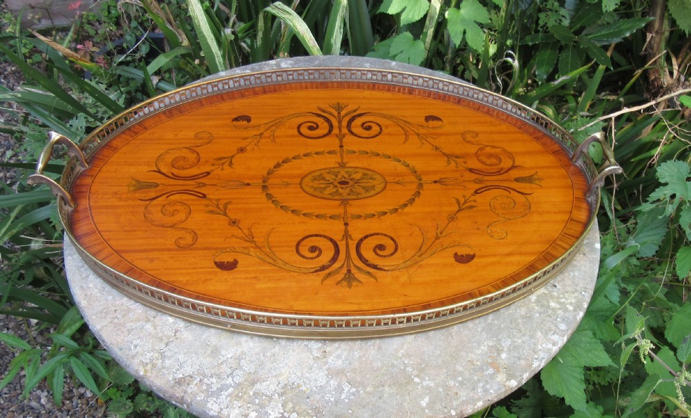 An oval satinwood serving tray featuring detailed central floral marquetry inlay, a pierced brass gallery rim, and two brass handles. View VI