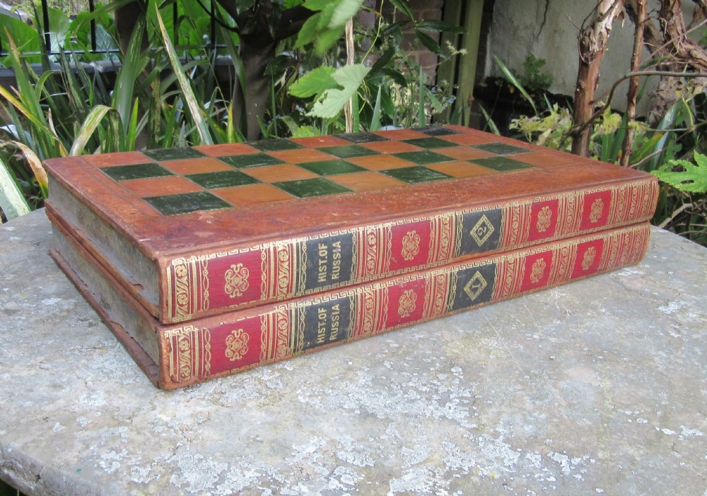 A Victorian folding leather games board designed to resemble two red volumes titled History of Russia with a green and brown chequered surface on top.