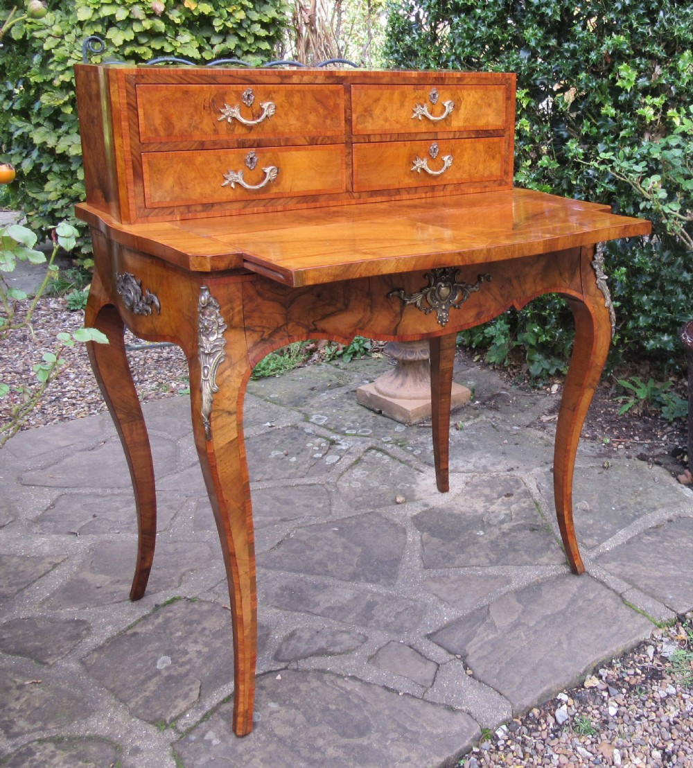 A figured walnut writing desk featuring a raised rear section with four drawers, slender cabriole legs, and decorative brass mounts. View III