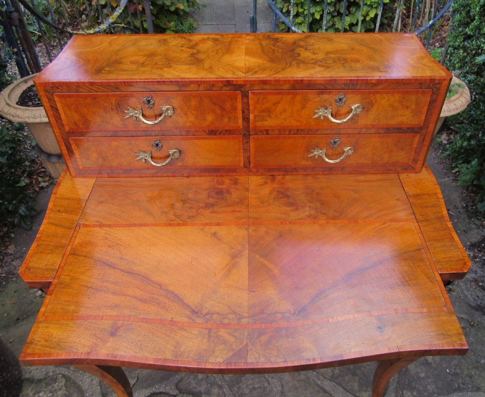 A figured walnut writing desk featuring a raised rear section with four drawers, slender cabriole legs, and decorative brass mounts. View IV