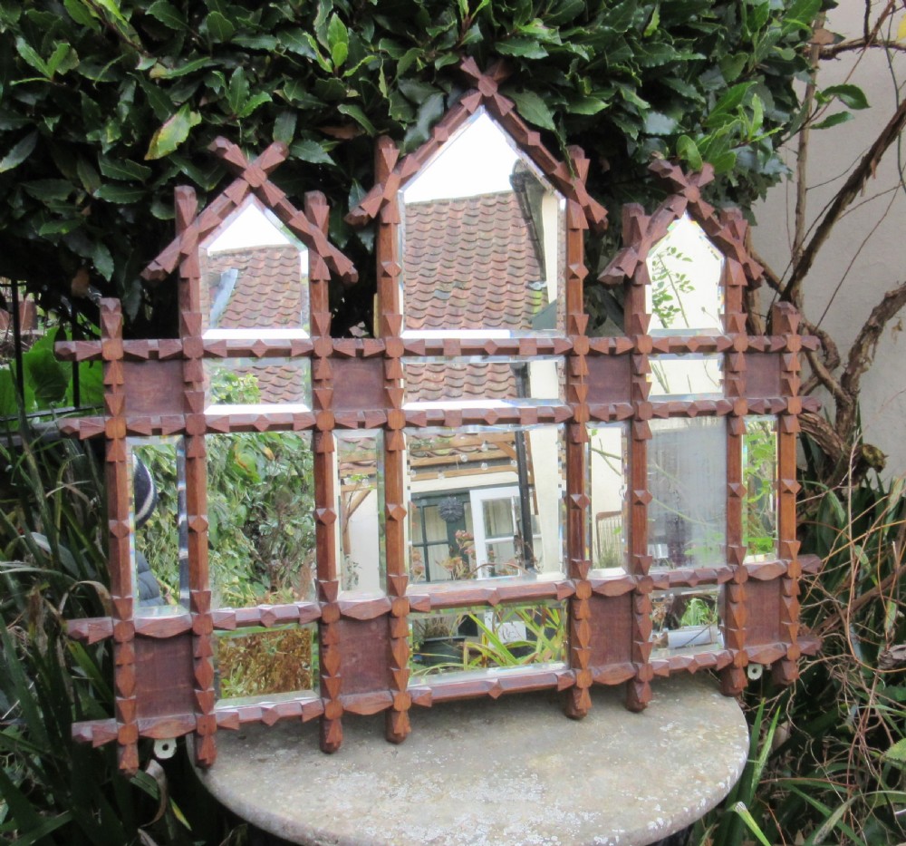 A Victorian Oxford Movement carved oak wall mirror featuring three gabled crests, a cross-hatched lattice structure, and multiple bevelled mirror plates.