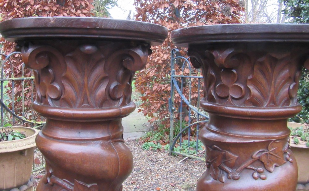 A pair of carved oak spiral column pedestals featuring acanthus leaf capitals, foliage relief carving, and square stepped plinth bases. View III