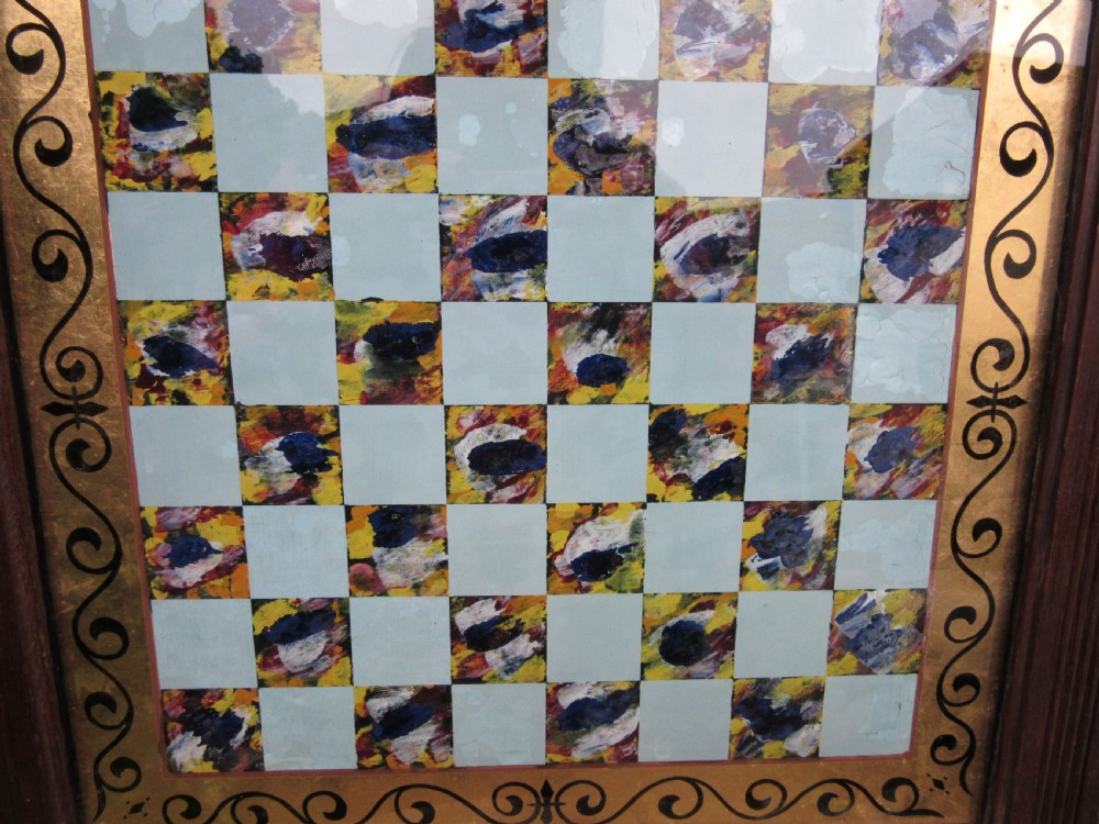 A square Victorian reverse-painted glass chess board with light blue and marbled squares, surrounded by a gilt scrollwork border and framed in dark moulded wood. View III