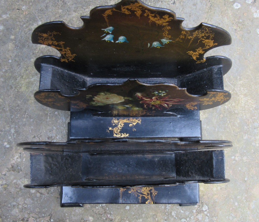 A pair of Regency black papier-mache letter stands decorated with hand-painted floral motifs and gilded foliage on stepped rectangular bases. View V