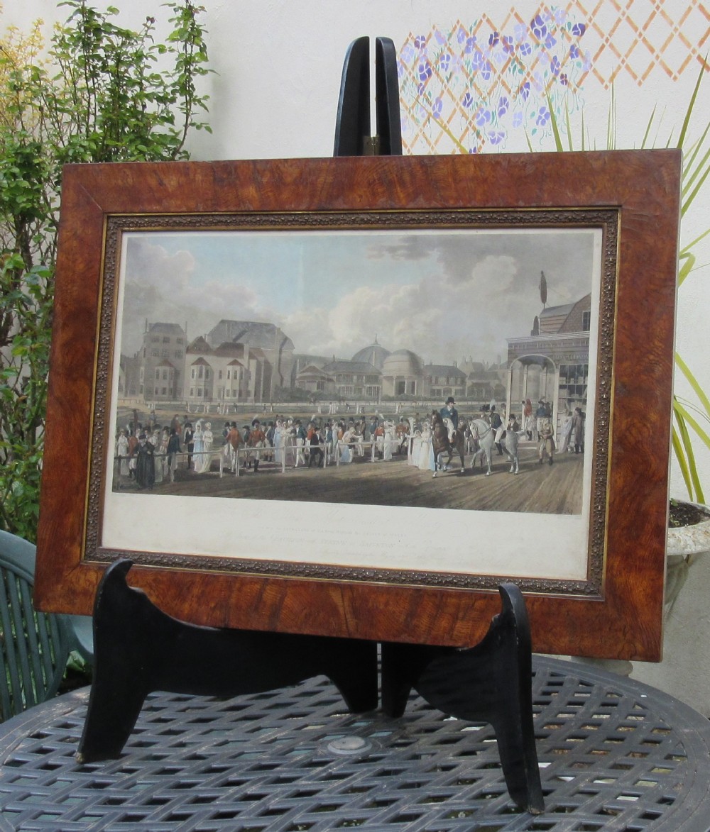 An 1806 engraving depicting figures promenading near the Royal Pavilion in Brighton, set within a wide brown timber frame with a gilded inner rim.