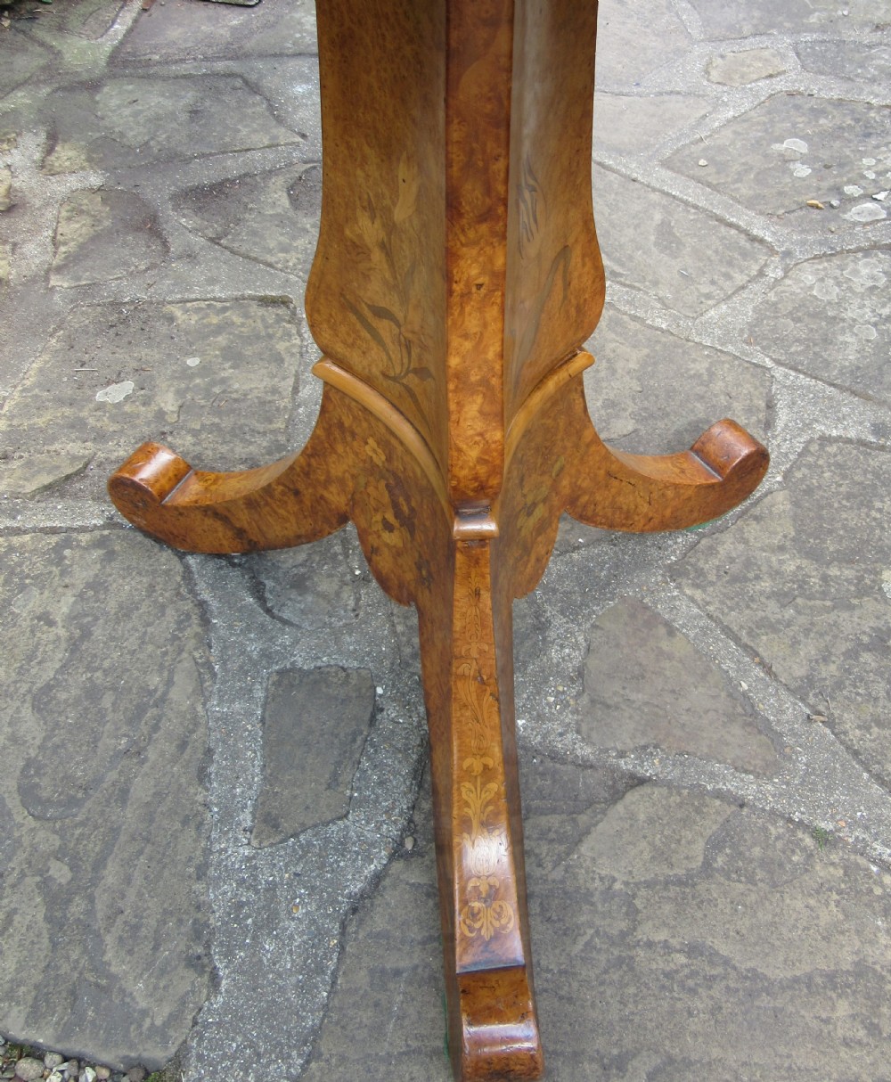 An early Victorian burr walnut tripod side table featuring a circular top, a tapered stem with inlaid floral motifs, and three splayed legs with scrolled feet. View VII
