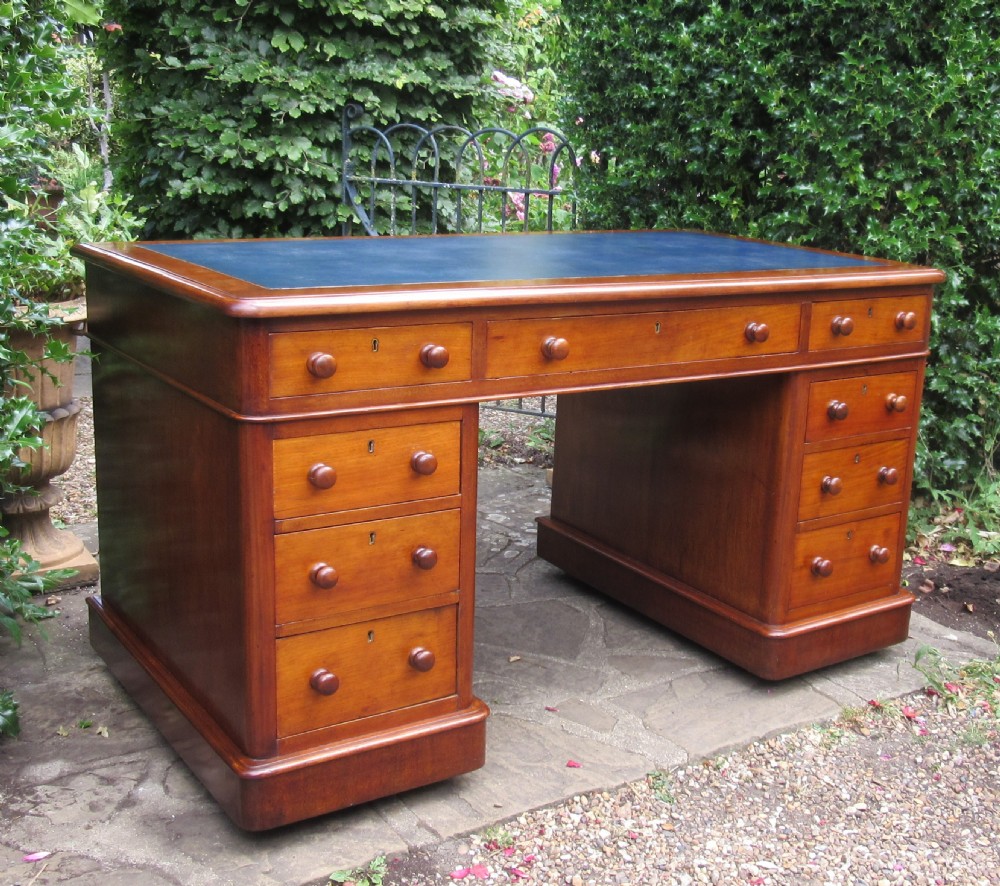 A nineteenth-century Victorian mahogany pedestal desk featuring a blue leather writing surface, multiple drawers with wooden turned handles, and twin pedestal supports. View II