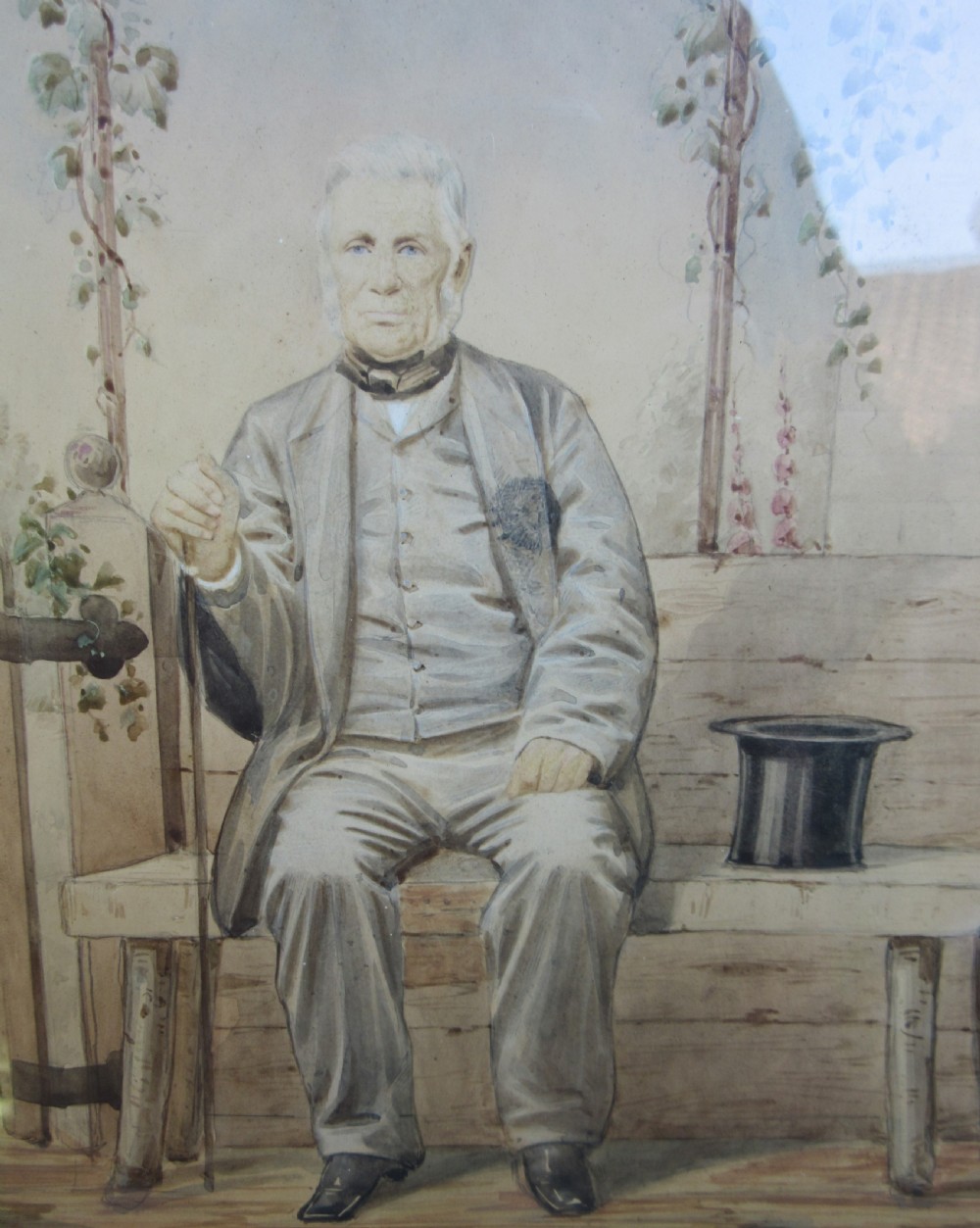 An antique primitive watercolour portrait painting depicting a seated gentleman in a garden setting within a detailed moulded frame. View III