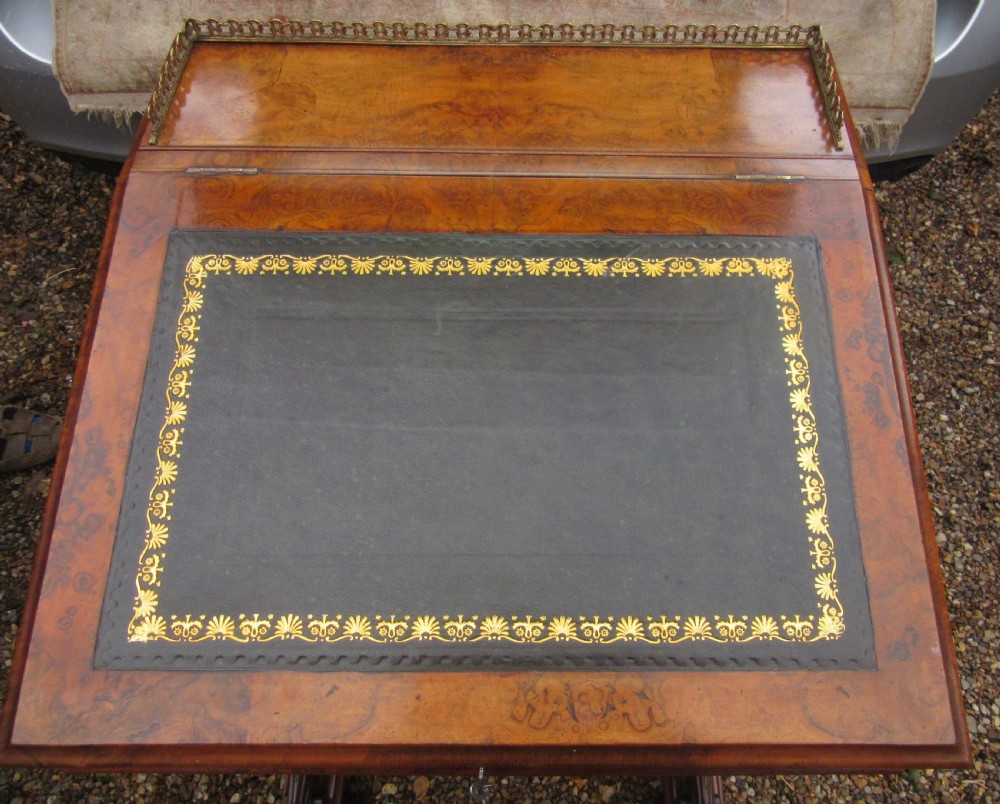 Victorian burr walnut davenport desk featuring a sloped leather writing top, carved scroll supports, side cupboard door, and brass gallery. View XI