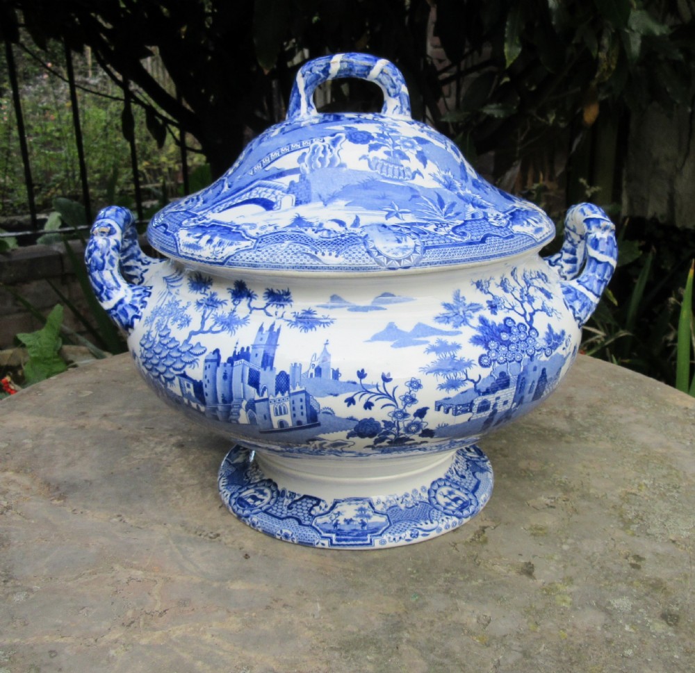 A blue and white transfer-printed ceramic tureen featuring a domed lid, side handles, and a pedestal base decorated with landscape scenes. View VI