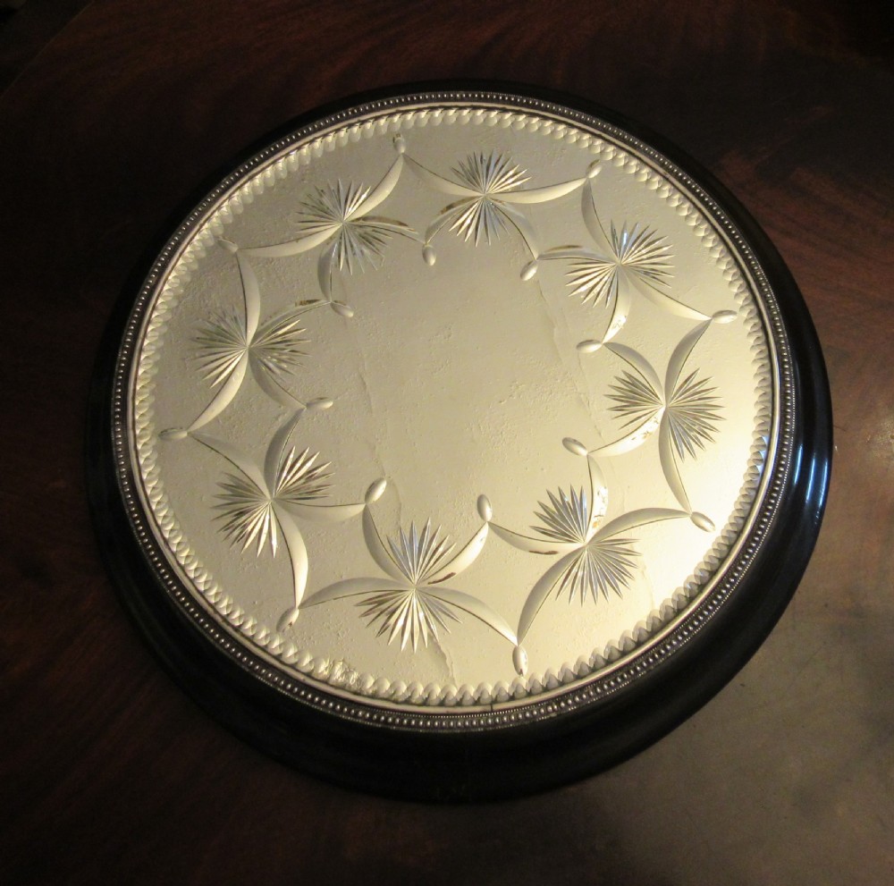 A circular Victorian mirrored table plateau featuring wheel-cut starburst patterns framed by a beaded metal rim on a turned ebonised wood base.