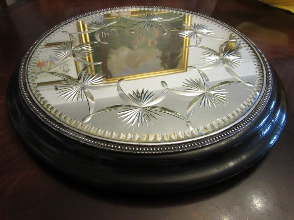 A circular Victorian mirrored table plateau featuring wheel-cut starburst patterns framed by a beaded metal rim on a turned ebonised wood base. View II