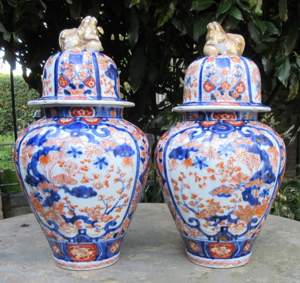 A pair of Victorian porcelain covered vases decorated with cobalt blue and rust red floral patterns topped with foo dog finials.