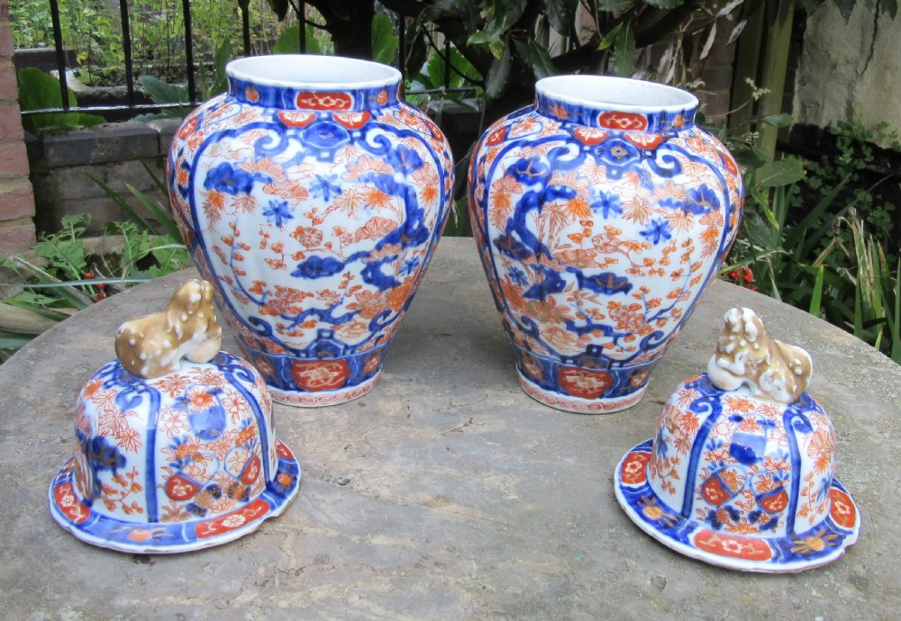 A pair of Victorian porcelain covered vases decorated with cobalt blue and rust red floral patterns topped with foo dog finials. View V