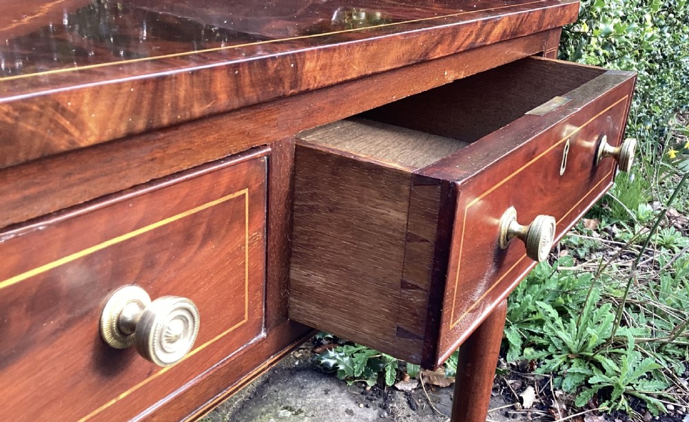 A late Georgian mahogany serving table with three inlay-decorated drawers, a low gallery back, and four turned legs. View IV