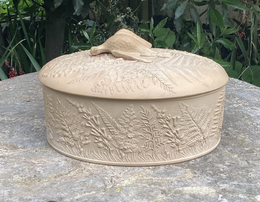 A 19th-century buff caneware game pie dish featuring raised fern leaf decoration around the body and lid with a game bird finial.
