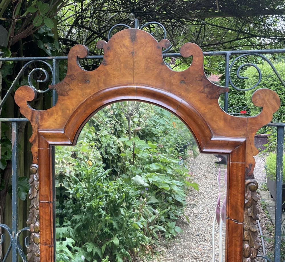 A Georgian style walnut wall mirror featuring a fret-cut scrollwork cresting, carved side foliage, and a bevelled glass mirror plate. View IV