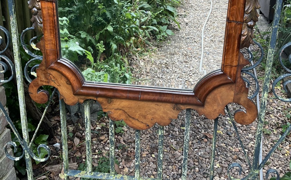 A Georgian style walnut wall mirror featuring a fret-cut scrollwork cresting, carved side foliage, and a bevelled glass mirror plate. View V