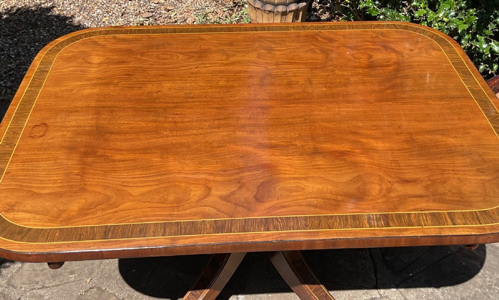 A Regency mahogany coffee table featuring an inlaid crossbanded top, central turned column, and splayed legs with brass castors. View III
