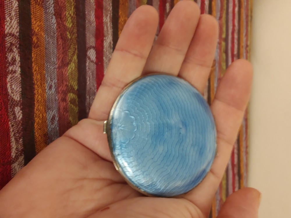 An oval Art Deco solid silver powder compact decorated with light blue guilloche enamel over a wavy engine-turned background. View II