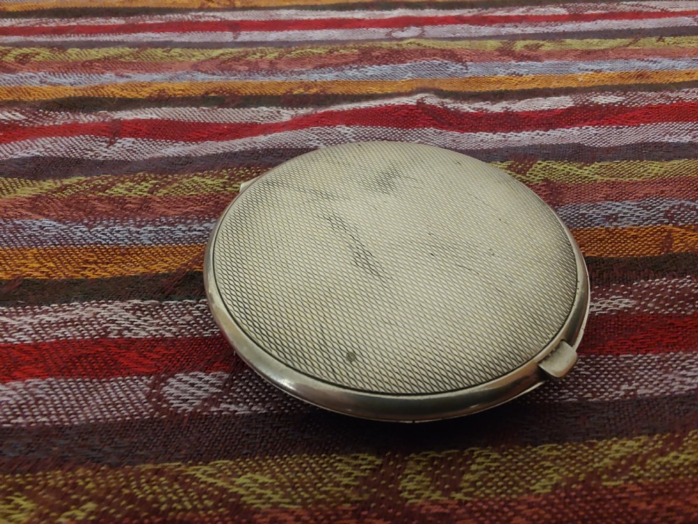 An oval Art Deco solid silver powder compact decorated with light blue guilloche enamel over a wavy engine-turned background. View V