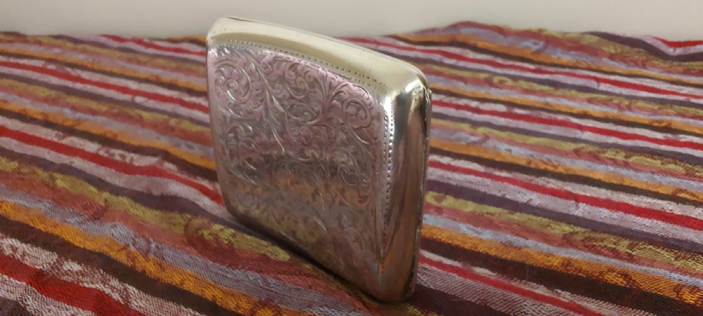 A square Victorian sterling silver cigarette case featuring hand-engraved foliate scrollwork and a blank central scalloped cartouche. View IV