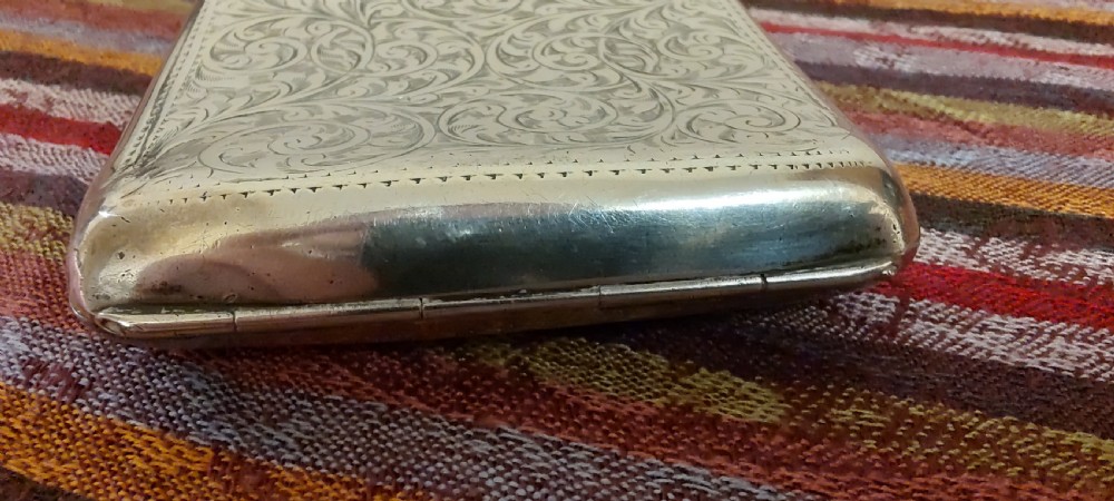 A square Victorian sterling silver cigarette case featuring hand-engraved foliate scrollwork and a blank central scalloped cartouche. View XII