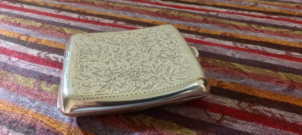 A square Victorian sterling silver cigarette case featuring hand-engraved foliate scrollwork and a blank central scalloped cartouche. View XIV